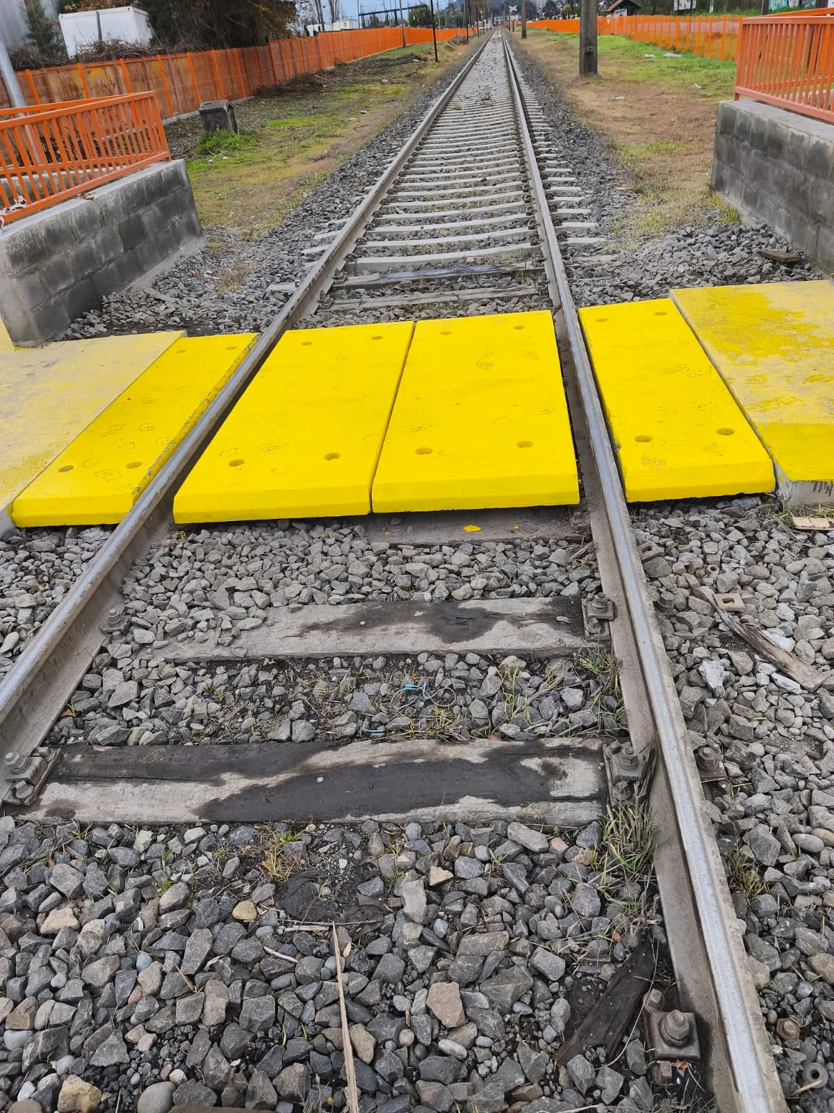Losetas de hormigón pintadas de amarillo instaladas en un cruce ferroviario, a nivel con los rieles